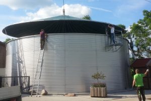 anaerobic digester cover being installed by several men